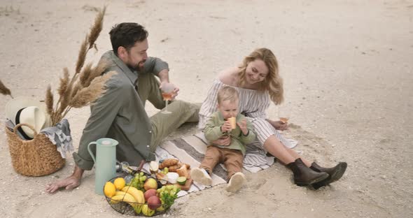 Happy man and woman spending weekend with child in the sea. Cheerful boy eat bread alt