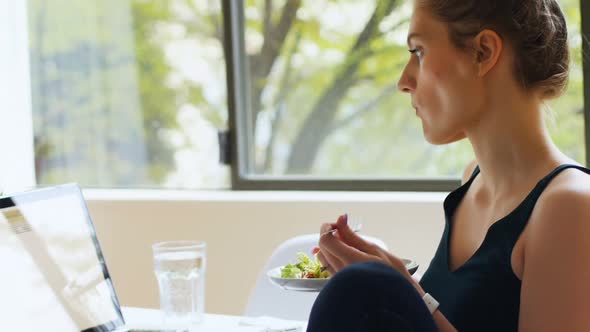 Woman eating salad while using laptop 4k