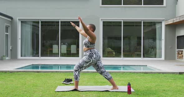 Happy african american plus size woman practicing yoga, standing stretching in garden