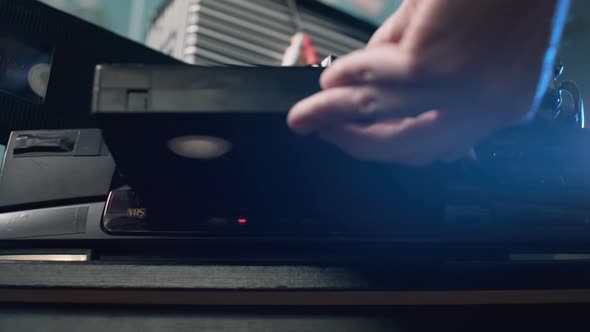 Closeup of Man Putting VHS Tape Into Video Player