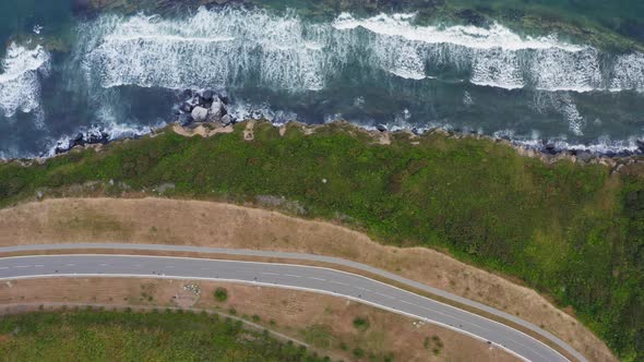 View From a Drone Vertically Down on an Empty Asphalt Road Along the Coast