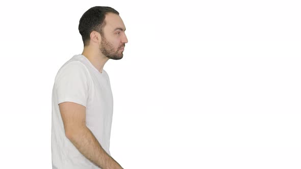 Sleepy Male in White Tshirt Yawning and Rubbing Eyes While Walking on White Background