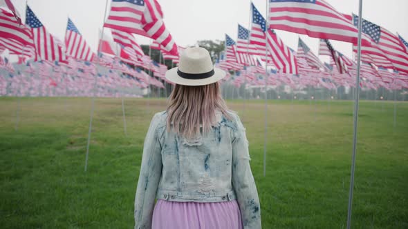 Camera Following Woman in Memorial Park with Many US Flags Flattering By Wind