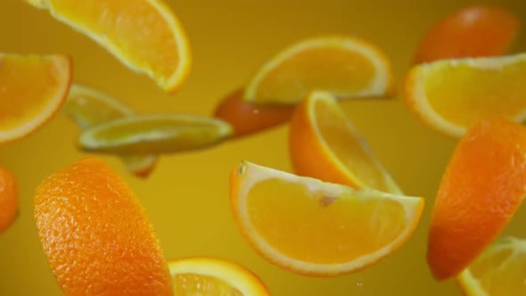 Juicy Slices of Orange Are Flying Up and Rotating on the Yellow Background