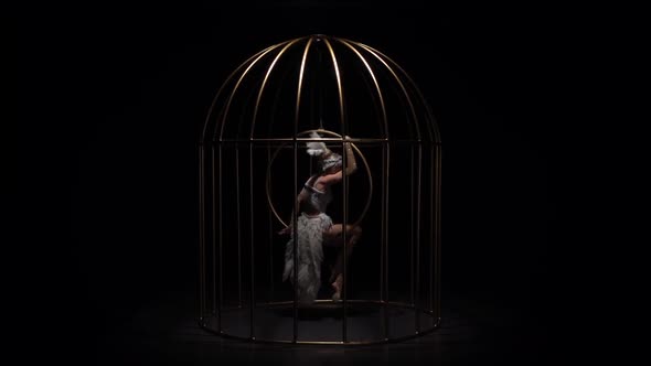 Graceful Girl Gymnast Riding a Hoop in a Cage on Dark Stage. Black Background. Slow Motion