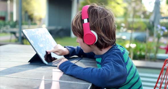 A young boy attempts to learn remotely on his laptop and headphones over distance learning due to th