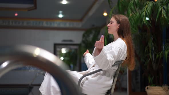 Side View Portrait of Smiling Relaxed Woman Meditating Sitting at Pool Indoors