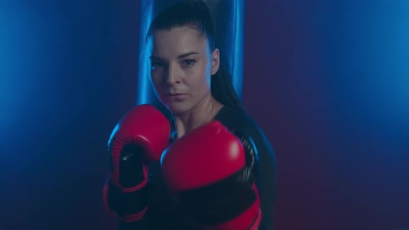 Beautiful  athletic woman boxer in boxing gloves calls her opponent to battle and smiles ironically