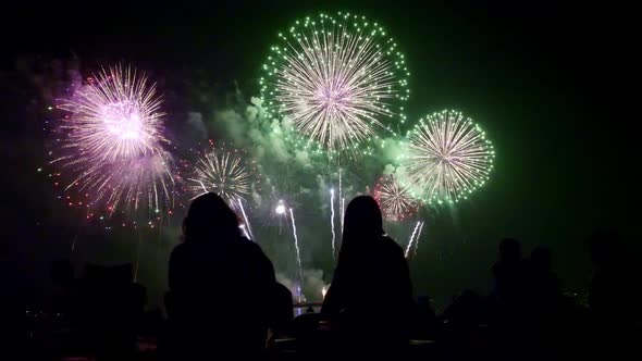 Crowd of silhouetted people watching fireworks show