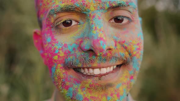 Closeup Slow Motion Portrait of Handsome Arab Guy with Painted Face Standing Outdoors at Holi