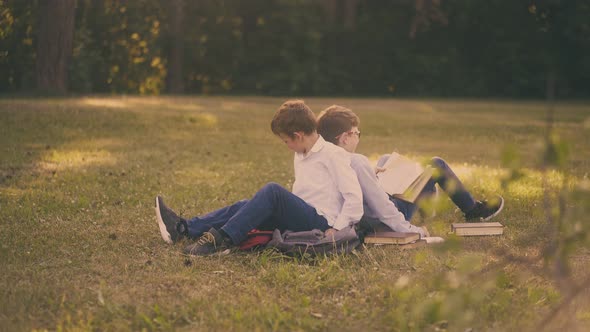 Schoolboys Jostle with Backs Holding Textbooks on Lush Grass