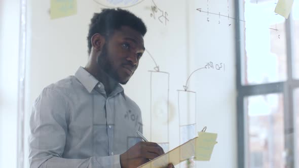 Businessman with Clipboard at Office Glass Wall 