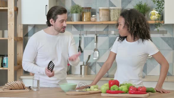 Young Man Arguing with Young African Woman in Kitchen