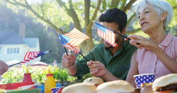 Family holding american flags during meal in the park 4k