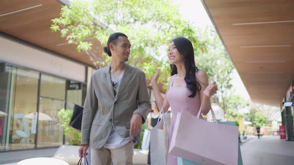 Asian young man and woman shopping goods outdoors in department store.