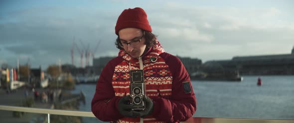 Young man using vintage camera taking shots and looking into the camera