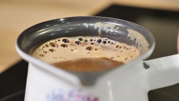 CoLast second of boiling coffee in slow motion and removing it before going over the edge of the pot