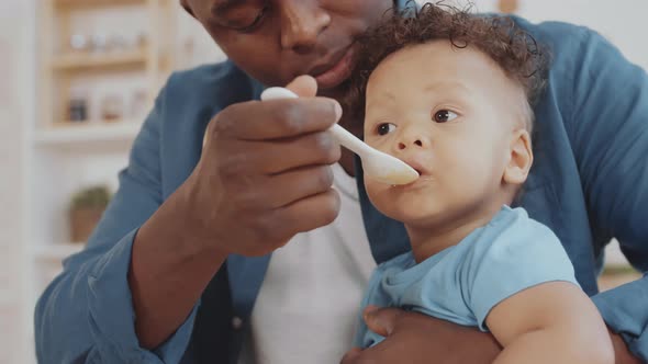 Young African Man Feeding Happy Infant