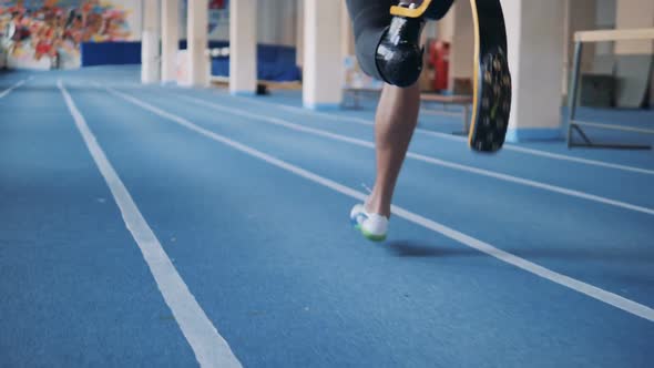 One Man with Bionic Leg Training on a Running Track, Back View