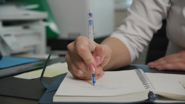 Young Female Doctor Writing Words in Cursive in Notebook with Blue Ink Pen