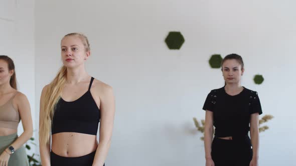 Four Attractive Ladies Doing Vrikshasana Tree Pose Lifting Arms Above Their Heads During a Yoga