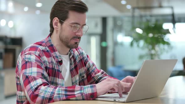 Male Designer with Laptop Smiling at Camera