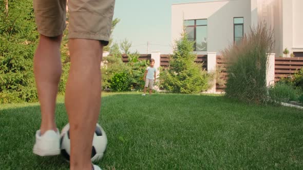 Dad And Son Playing Football In Backyard