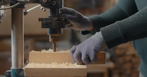Woodworker Drills Holes in Wooden Plank with Drilling Machine in Slow Motion Carpentry at Workshop