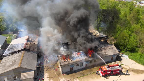 Aerial View of Firefighters Extinguishing Ruined Building on Fire with Collapsed Roof and Rising
