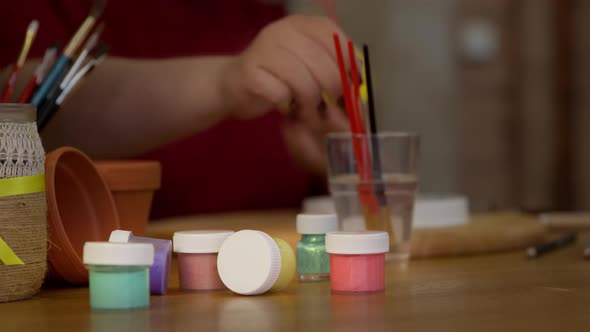 Jars with Multi-colored Oil Paints and Jar with Paintbrushes Are on the Table