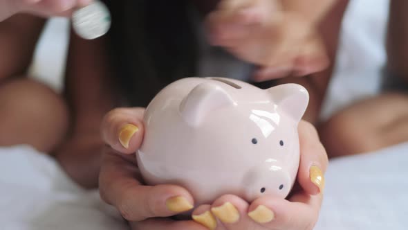 Mother and Children Putting Coins Into Piggy Bank for the Future Savings