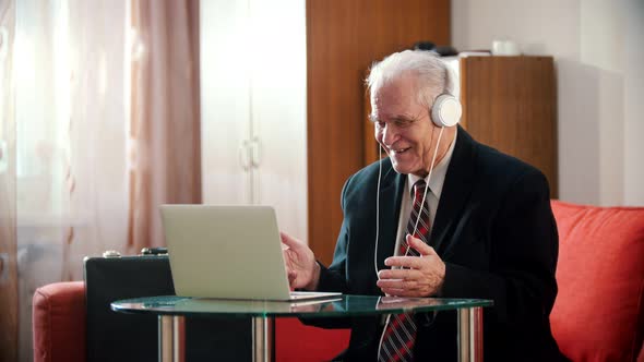 Elderly Grandfather - Old Grandfather in Headphones Smiling and Looking at Laptop Screen in His
