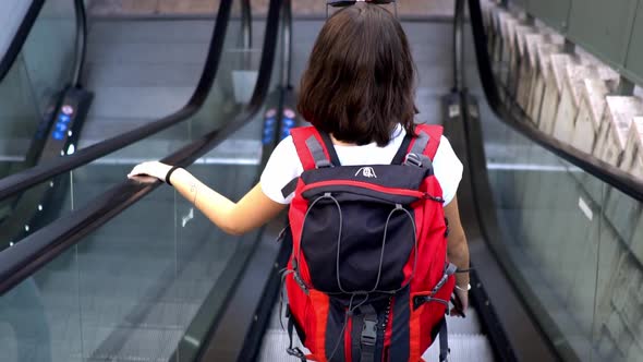 Female tourist with backpack on escalator