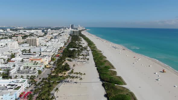 White Sand And Blue Water Of Miami Beach With Skyscrapers Of Downtown Miami In Florida. aerial, pull