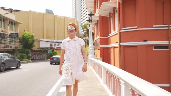 4K Confidence Asian lgbtq guy wearing woman clothes with sunglasses walking down city street.