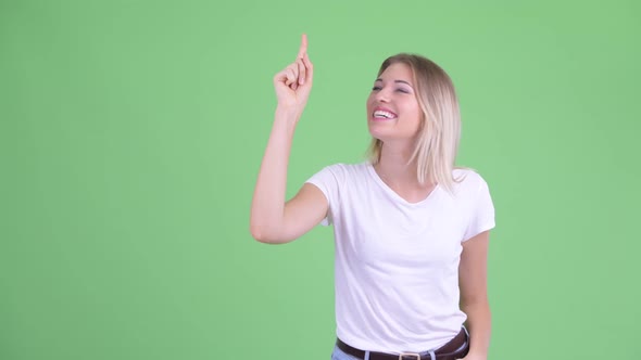 Happy Young Beautiful Blonde Woman Talking While Pointing Up