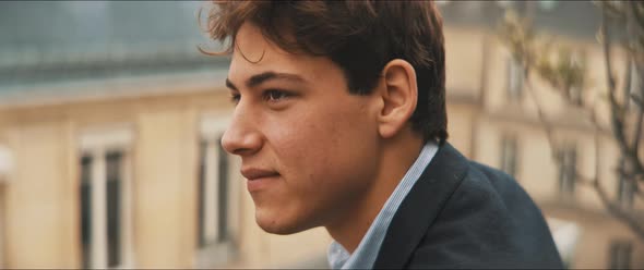 Close up of a young man smiling and staring outdoors