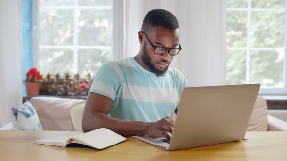 African American Businessman Using Laptop at Modern Home Office.