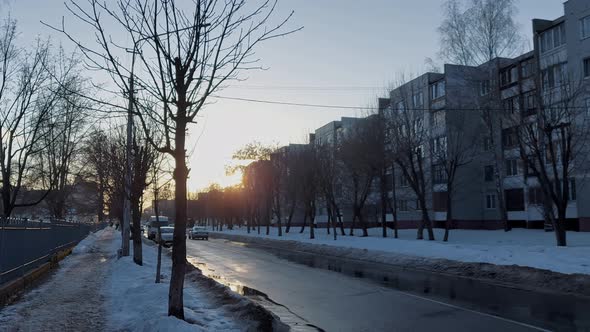 Car Drives Along a Narrow Street in Winter in a Residential Area with Multistorey Buildings in the