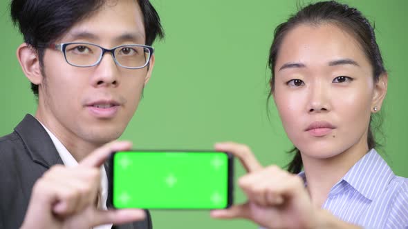 Young Asian Business Couple Showing Phone Together