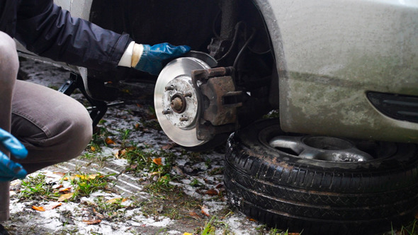 Man Taking Wheel Off The Car On Lifting Jack