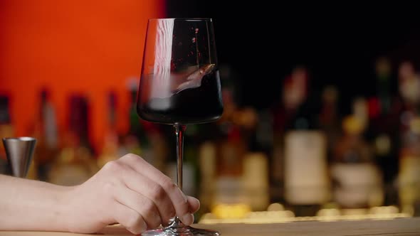 Barman Rotates Glss with Red Wine in Slow Motion Sommelier Mixing Red Wine in Glass Evaluating Color