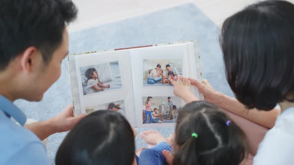 Asian family look at photographs on old picture album recalls the past.