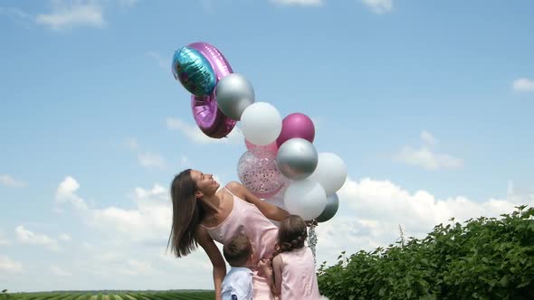 Happy Family Holding Hands Walking on the Green Lawn of the Park Opened with Balloons in Hands