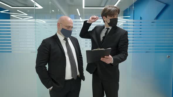 Portrait of Young Caucasian Elegant Man Standing in Office Corridor with Middle Aged Business