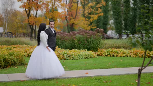 with Long Dark Hair are Walking Along the Path of the Autumn Park