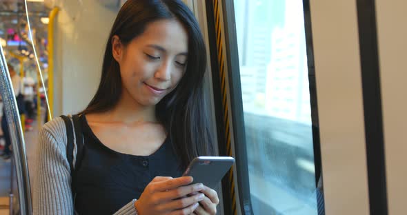 Woman use of smart phone on train in Hong Kong city