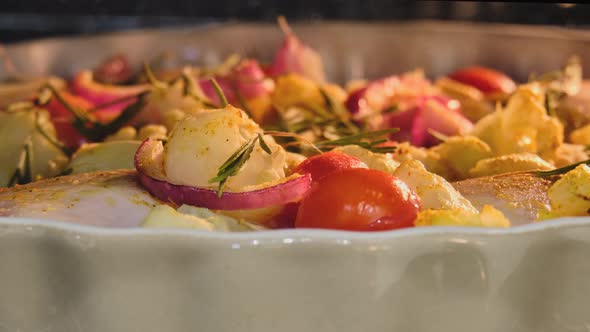 Chicken with vegetables, herbs and tomatoes is baked in the oven in a home kitchen, timelapse