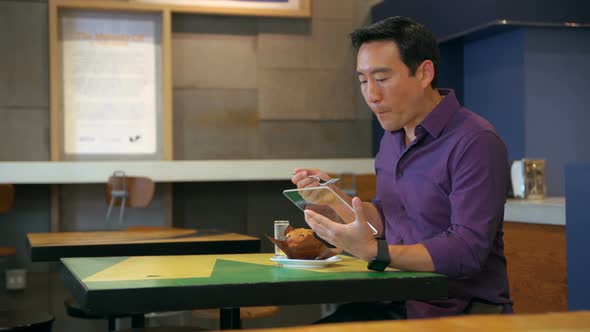 Man having food while using glass digital tablet 