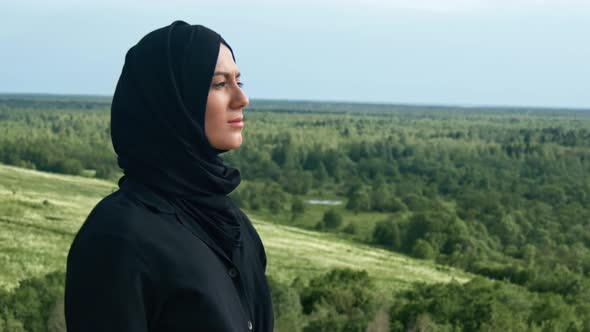 Pleasant Muslim Woman Breathing Freedom Inspiration on Top of Mountain Over Green Grass Forest